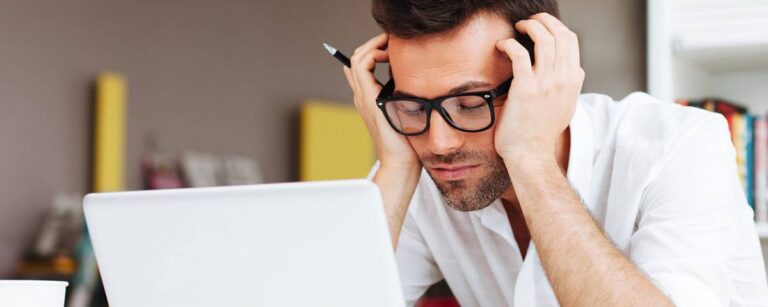 Man in front of a computer resting his eyes