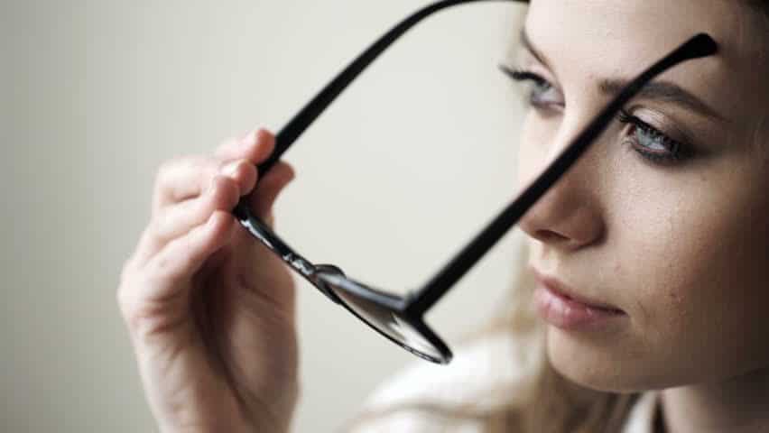 Woman putting on or removing eyeglasses