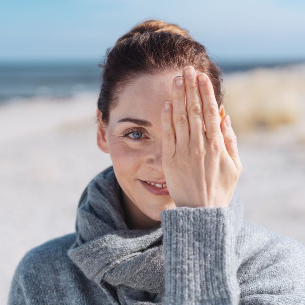 Woman on a beach with hand over her eye