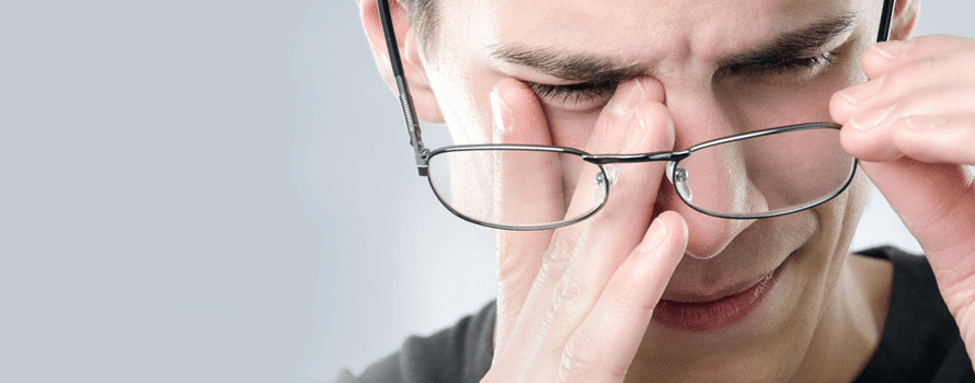 Man rubbing his eyes under glasses