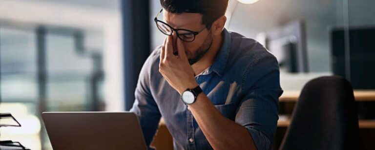 Man rubbing his eyes under glasses